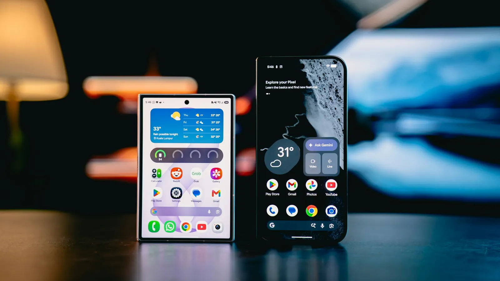 Two smartphones with lit screens standing on a dark table